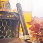 Rocky Patel Cigars The Edge Corojo Toro Single Cigar Leaning Against Full Box of Cigars
