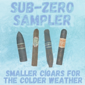 Four small premium cigars displayed on an icy blue background with frost details. At the top, large frozen-style text reads “Sub-Zero Sampler.” At the bottom, text says “Smaller Cigars for the Colder Weather.” The cigars shown are Oliva Nub Maduro, Caldwell Long Live The King Manzanita, Kristoff Cameroon Figurado, and Rocky Patel Catch 22 Rothschild.
